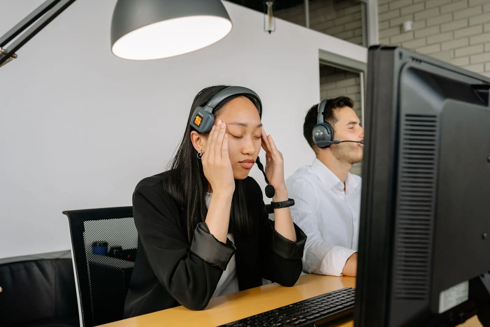 Tired person rubbing their eyes in front of a computer screen